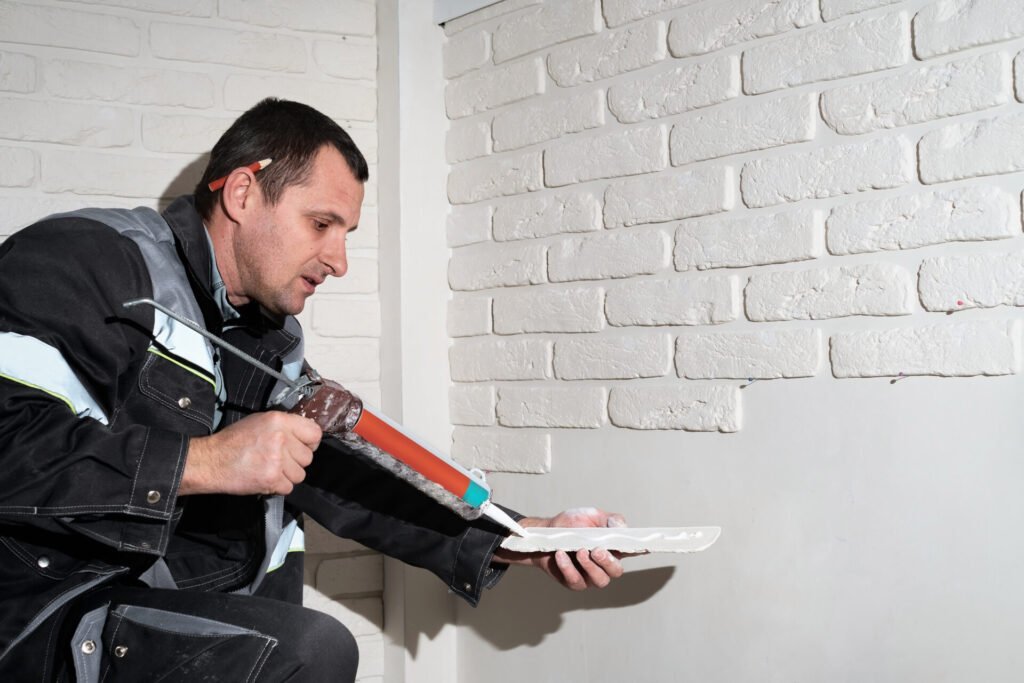 Thermal & Moisture Protection Estimating Services 2 Master applies glue tiles for facing the house. The master builder decorates the walls of the apartment. Finishing the building with modern materials.